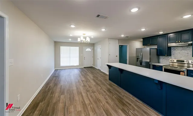 a large kitchen with stainless steel appliances a large counter top a stove and a wooden floors