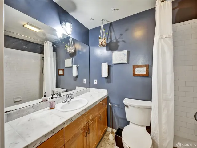 a bathroom with a granite countertop sink mirror vanity and toilet