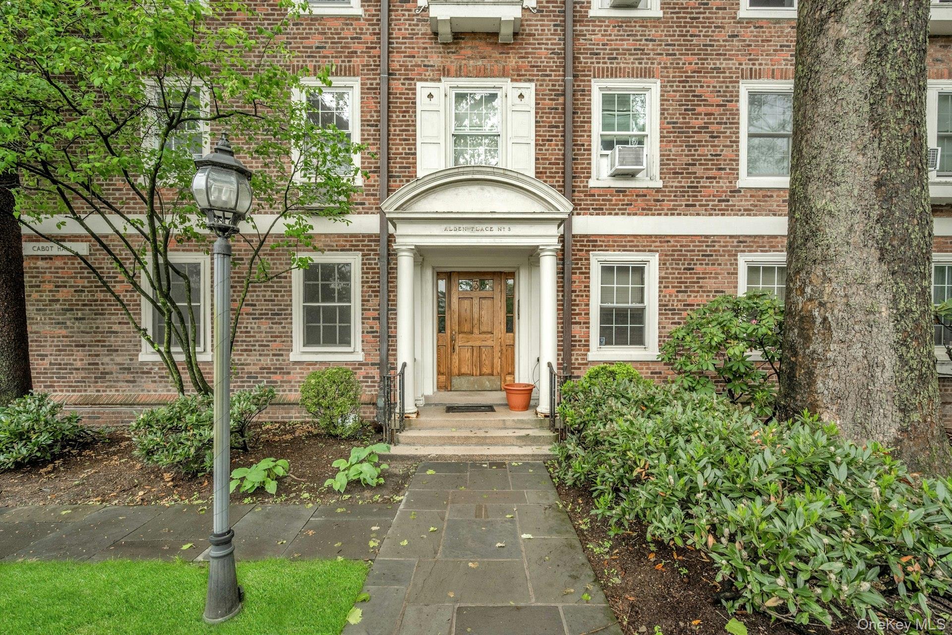 3 Alden Place, Unit 1A Bronxville, NY 10708 - Photo 3 of 29 front view of a brick house with a large window and potted plants