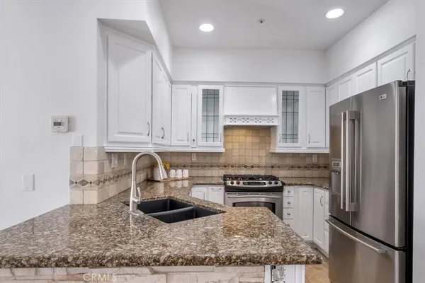 a kitchen with stainless steel appliances granite countertop a refrigerator sink and stove