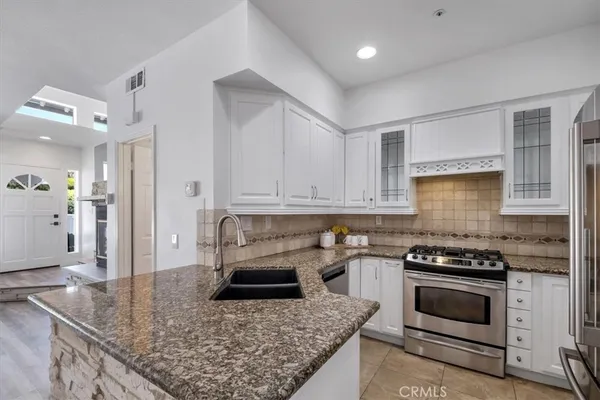 a kitchen with granite countertop a sink a stove and cabinets