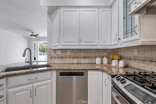 a kitchen with granite countertop a sink stove and cabinets