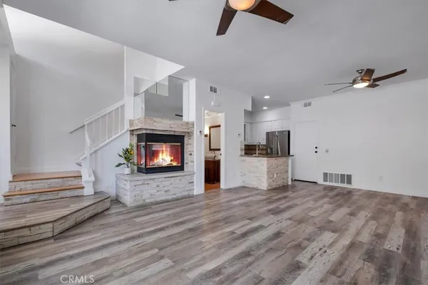 an empty room with wooden floor fireplace and windows