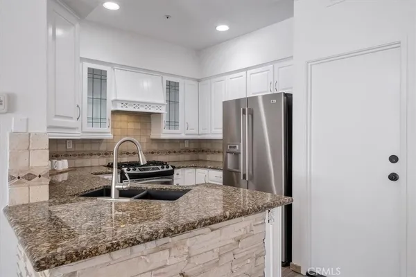 a kitchen with granite countertop a refrigerator and a sink