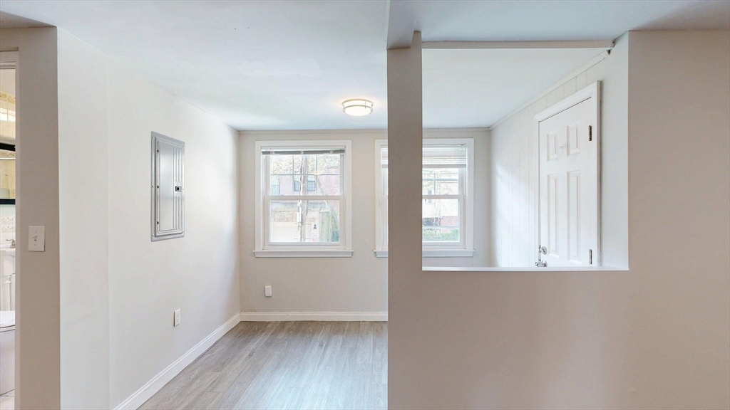 187 Maverick Street, Unit 3 Boston, MA 02128 - Photo 3 of 11 an empty room with wooden floor and windows