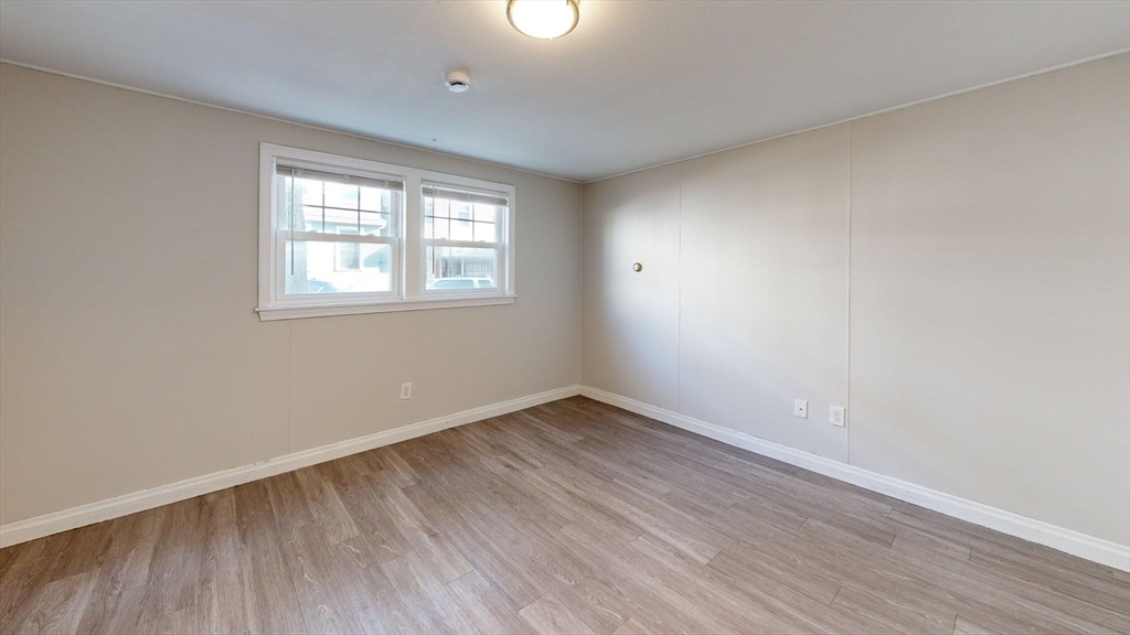 187 Maverick Street, Unit 3 Boston, MA 02128 - Photo 7 of 11 an empty room with wooden floor and windows