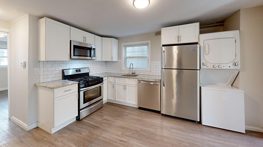 187 Maverick Street, Unit 3 Boston, MA 02128 - Photo 8 of 11 a kitchen with white cabinets white stainless steel appliances and wooden floors