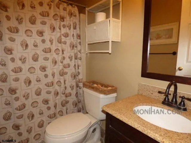 a bathroom with a granite countertop sink and a toilet