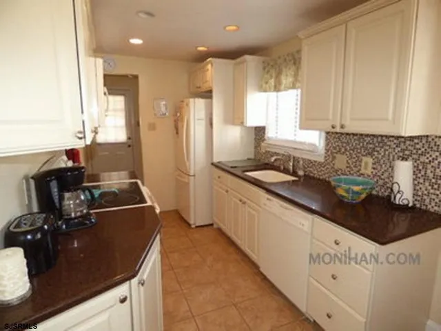 a kitchen with granite countertop a sink stove and cabinets