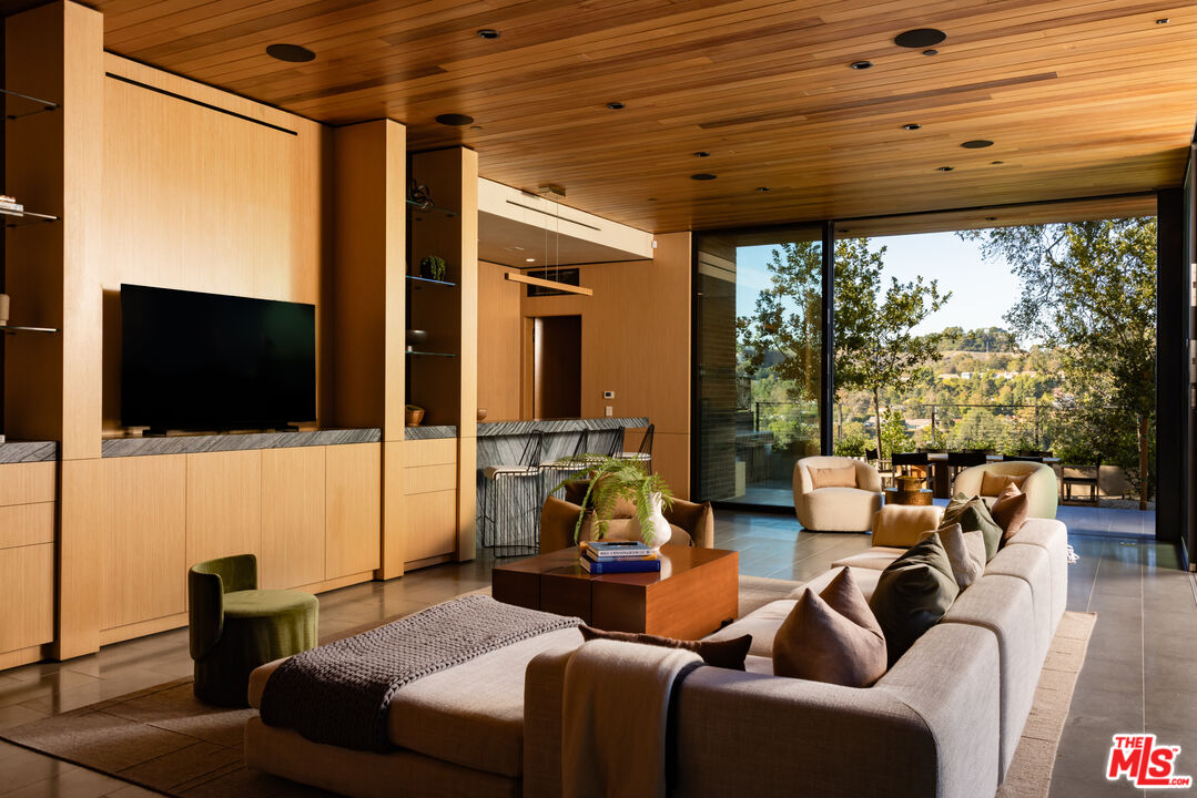 9705 Oak Pass Road Beverly Hills, CA 90210 - Photo 4 of 22 a living room with furniture a flat screen tv and floor to ceiling window