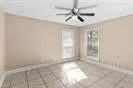 en empty room with windows and chandelier fan