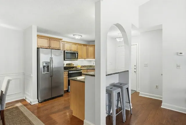 a kitchen with stainless steel appliances granite countertop a refrigerator a stove and a sink