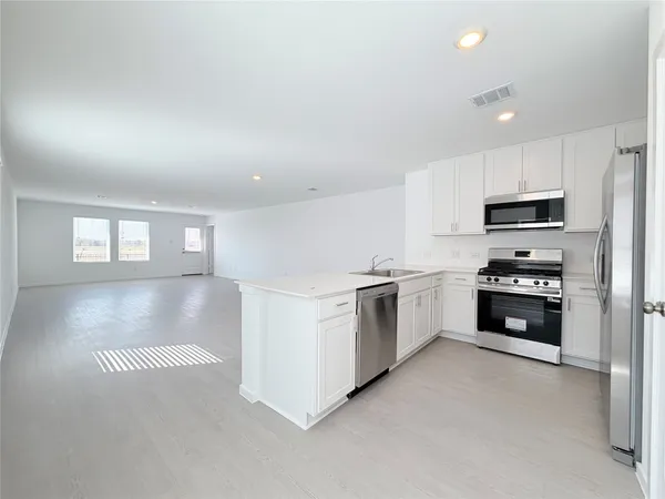 a view of a kitchen with kitchen island a sink wooden floor and black appliances