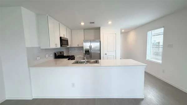 an empty room with kitchen view and windows