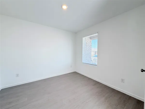 a view of a hallway with wooden floor and a bathroom