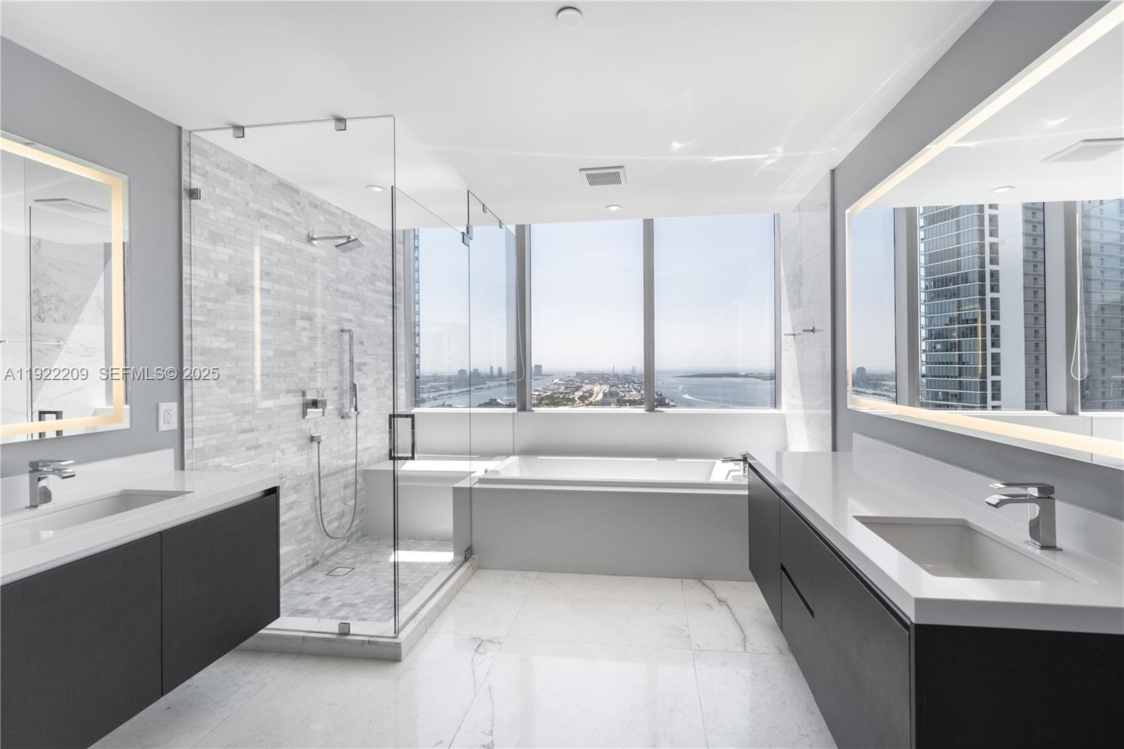 851 Northeast 1st Avenue, Unit 3911 Miami, FL 33132 - Photo 20 of 75 a bathroom with a double vanity sink a large mirror and a bathtub
