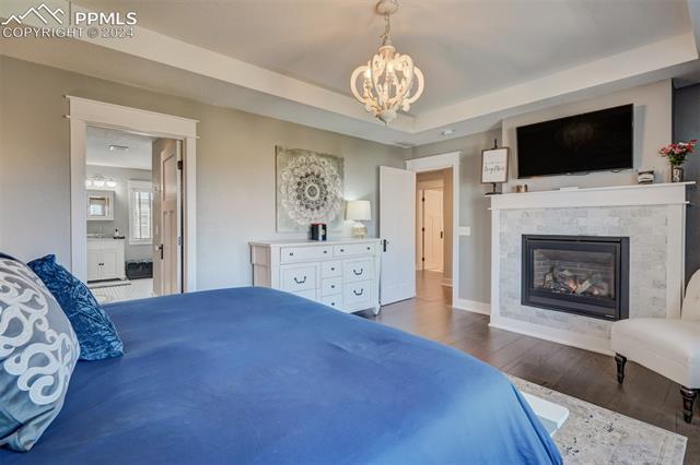 24076 Kobilan Road Calhan, CO 80808 - Photo 18 of 50 Bedroom featuring dark hardwood / wood-style flooring, an inviting chandelier, and a raised ceiling