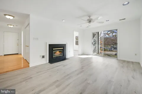 an empty room with wooden floor fireplace and windows