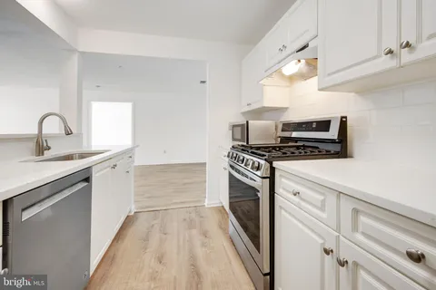 a kitchen with granite countertop a sink cabinets and stainless steel appliances