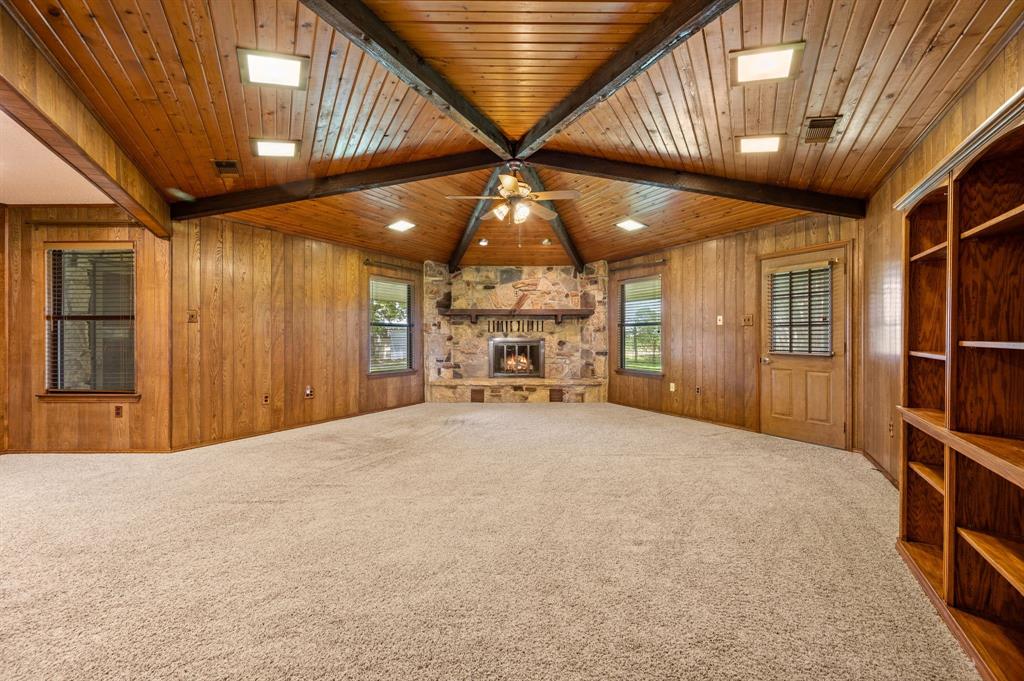 515 New Highland Road Springtown, TX 76082 - Photo 9 of 38 Spacious interior featuring wood-paneled walls and a vaulted wood-finish ceiling with exposed beams