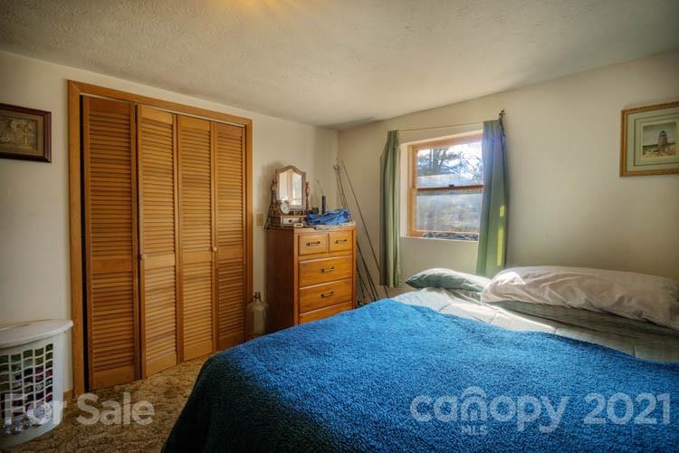4904 Crabtree Mountain Road Clyde, NC 28721 - Photo 20 of 37 a bedroom with a bed and a dresser next to a window