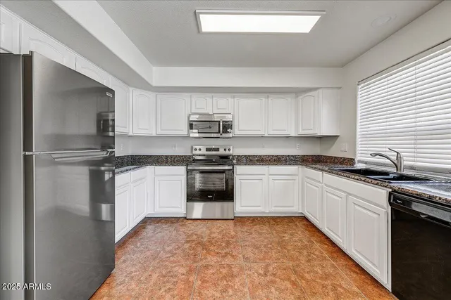a kitchen with granite countertop a refrigerator and a stove top oven