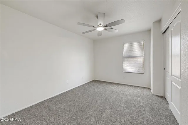 an empty room with windows and fan chandelier