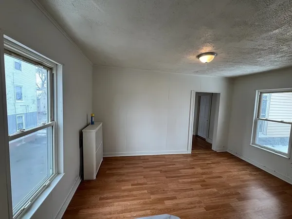 a view of an empty room with wooden floor and a window