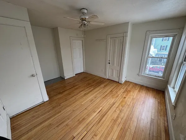 a view of empty room with wooden floor and fan
