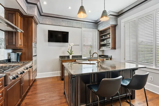 a kitchen with stainless steel appliances granite countertop a sink a stove a refrigerator cabinets and chairs