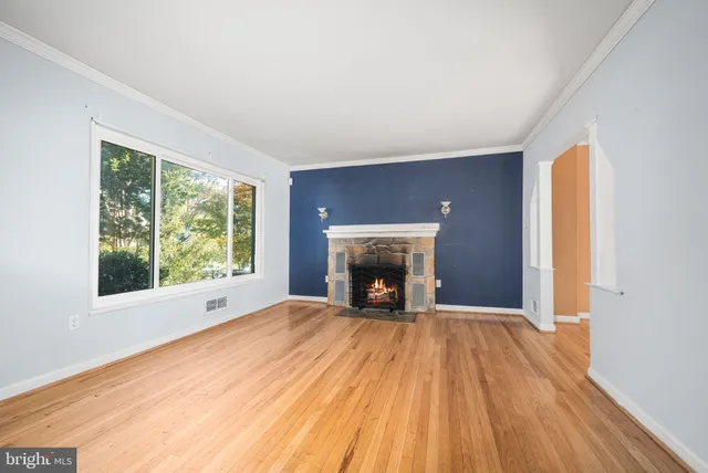 a view of empty room with wooden floor and fireplace