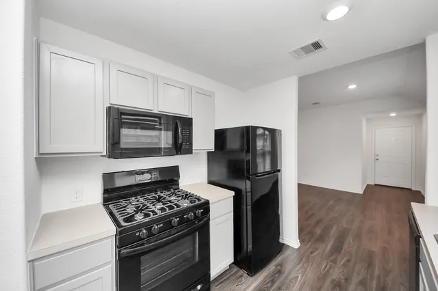 a kitchen with stainless steel appliances a stove a microwave and a hard wood floors