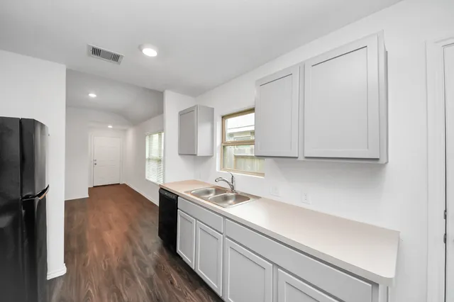 a kitchen with a sink a refrigerator and white cabinets