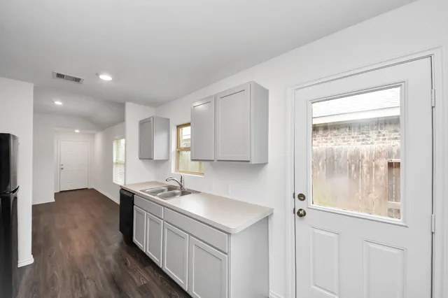 a kitchen with granite countertop a sink cabinets and wooden floor