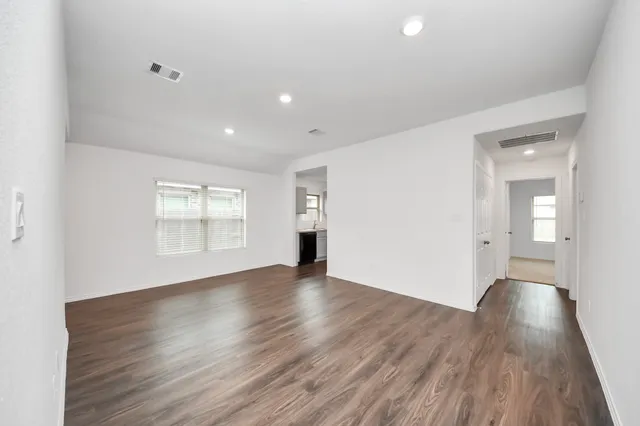 a view of an empty room with wooden floor and a window