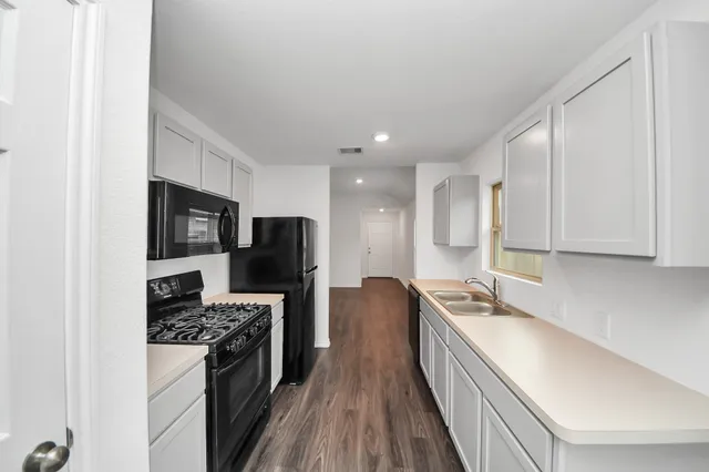 a kitchen with stainless steel appliances granite countertop a stove top oven a sink dishwasher a refrigerator and cabinets with wooden floor