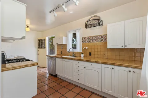 a kitchen with a sink a stove cabinets and a counter top space