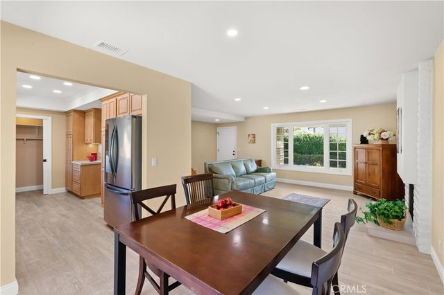 a living room with stainless steel appliances furniture dining table and wooden floor