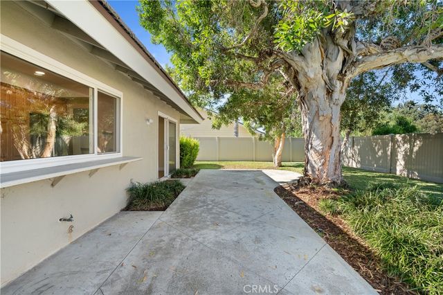 a view of a house with a yard and large tree