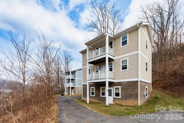 a view of a white house with a large tree