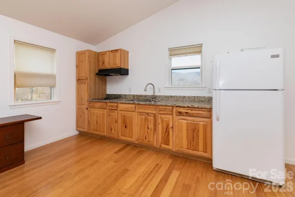 a kitchen with granite countertop a sink cabinets and wooden floor