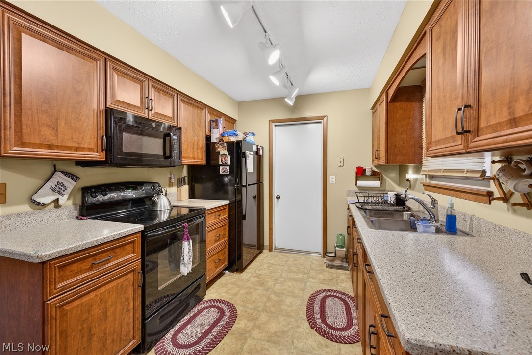 4404 Florida Street Perry, OH 44081 - Photo 7 of 24 Kitchen with black appliances, wood finish cabinets, rail lighting, and light stone counters