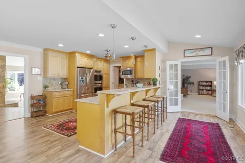 a living room with stainless steel appliances furniture wooden floor and a rug
