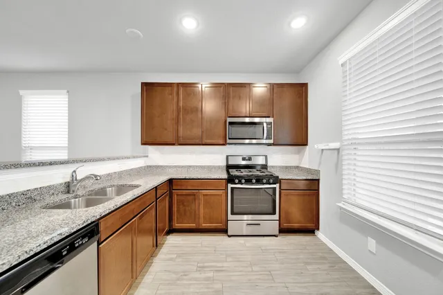 a kitchen with stainless steel appliances granite countertop a sink stove and refrigerator