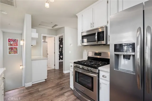 a kitchen with stainless steel appliances white cabinets a stove a microwave and a refrigerator