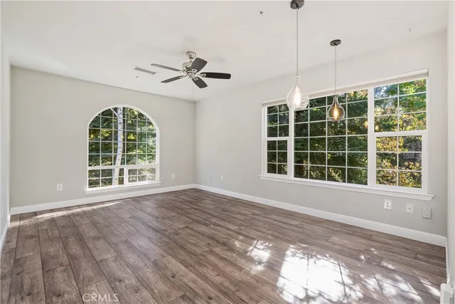 a view of an empty room with a window and wooden floor