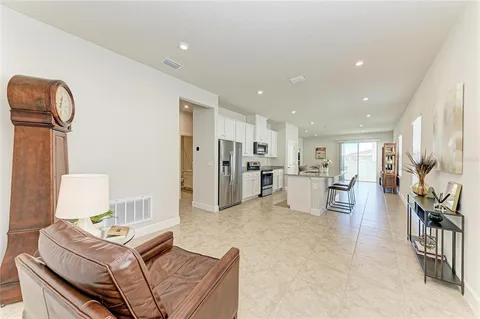 a living room with furniture a table and kitchen view