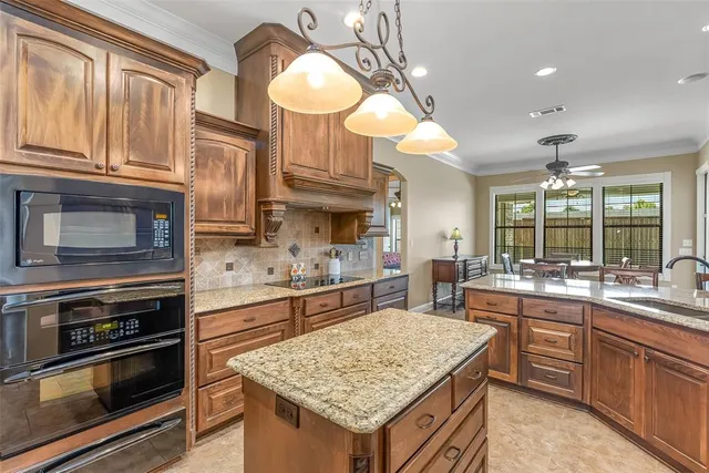 a kitchen with kitchen island granite countertop wooden cabinets a stove and a sink