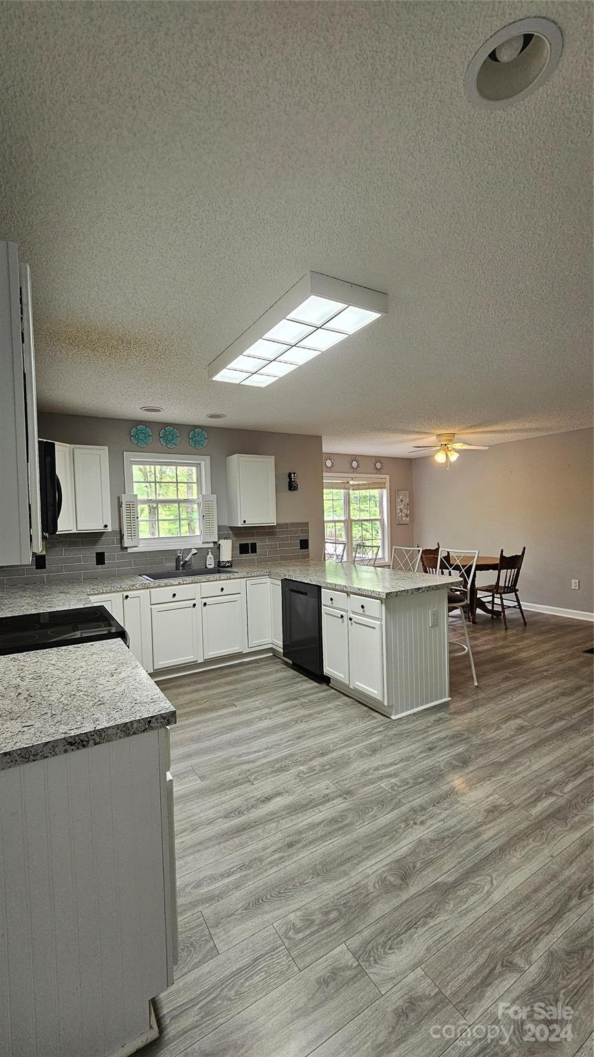 5013 Medlin Road Monroe, NC 28112 - Photo 16 of 30 a large kitchen with kitchen island a stove a sink dishwasher and white cabinets with wooden floor