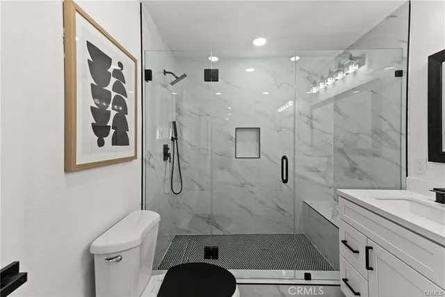 a bathroom with a granite countertop sink a toilet a shower and a mirror